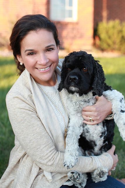 A woman is holding a black and white dog in her arms.