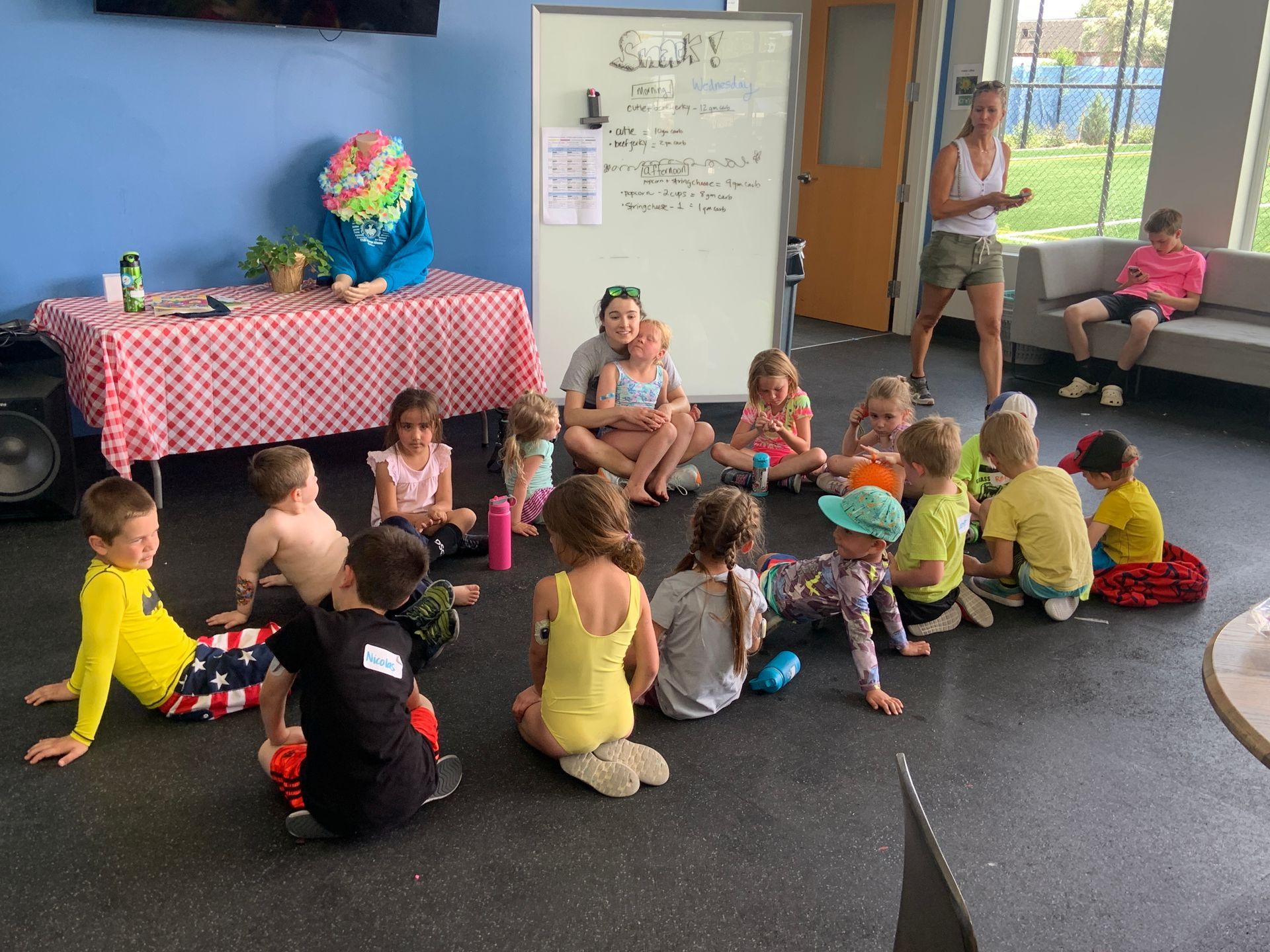 A group of children are sitting in a circle on the floor in a room.