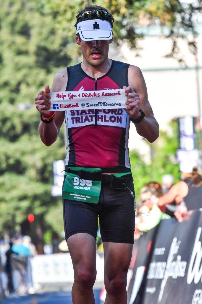 A man is running in a triathlon and holding a sign.