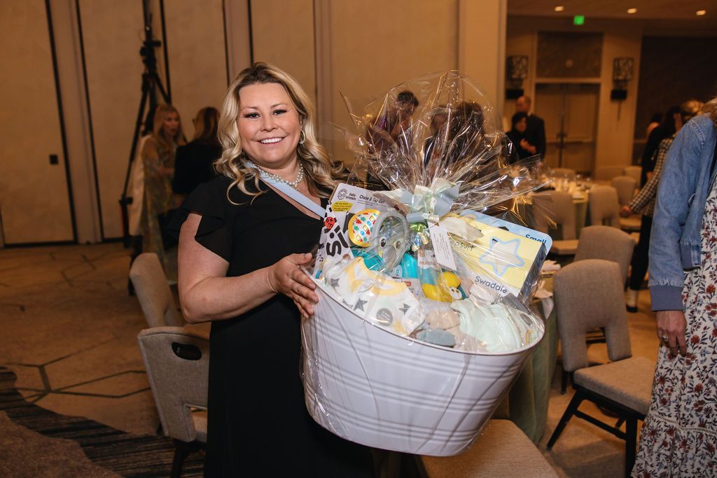 Woman holds an auction basket at the Brass Ring Luncheon and Fashion Show. 