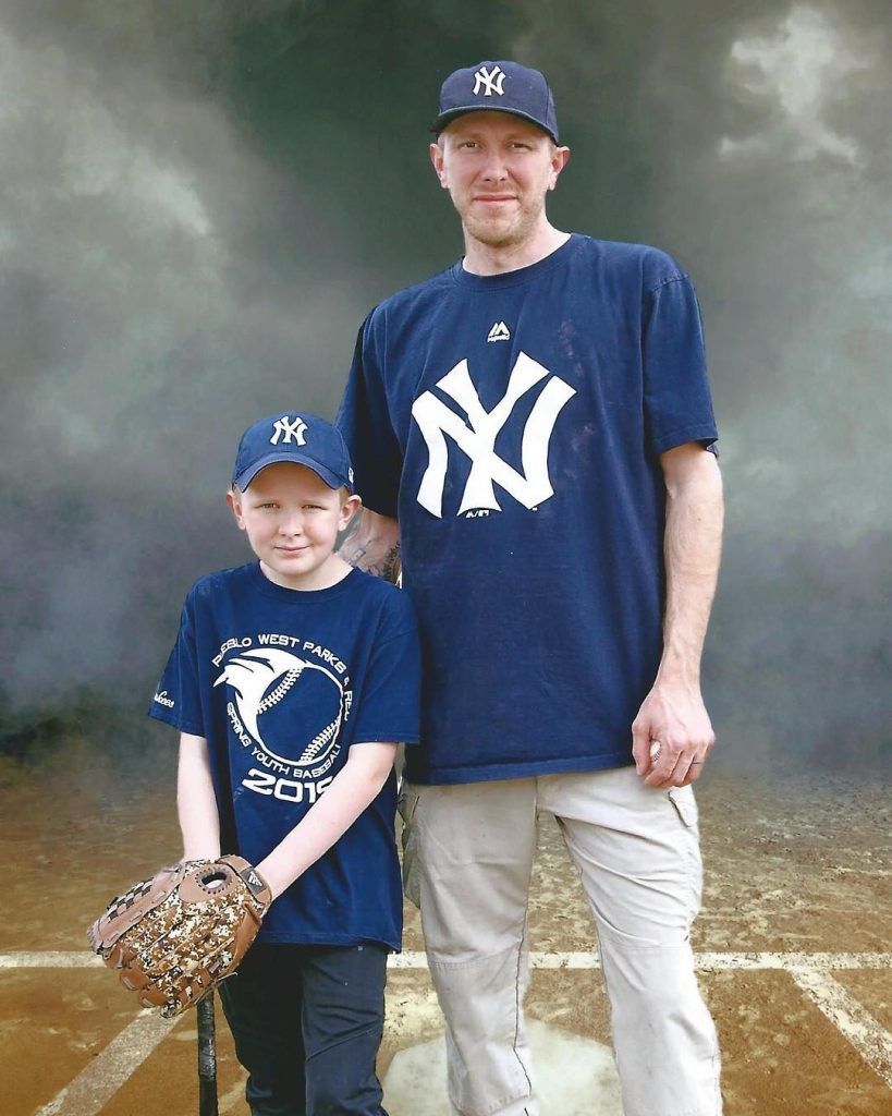 A man and a boy wearing ny yankees shirts pose for a picture