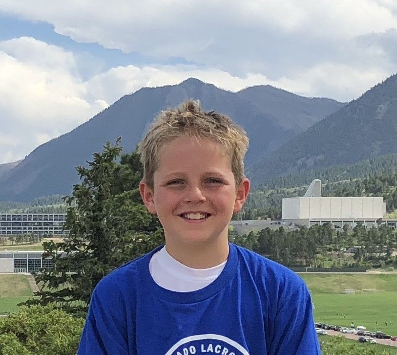 A young boy wearing a blue shirt with the word lacrosse on it
