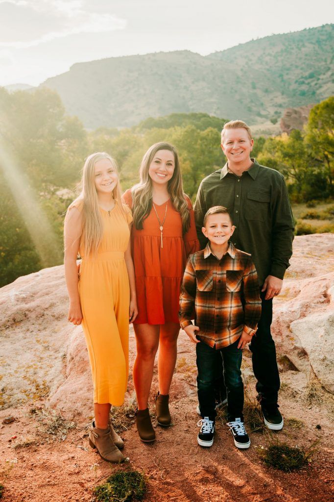 A family is posing for a picture on top of a mountain.