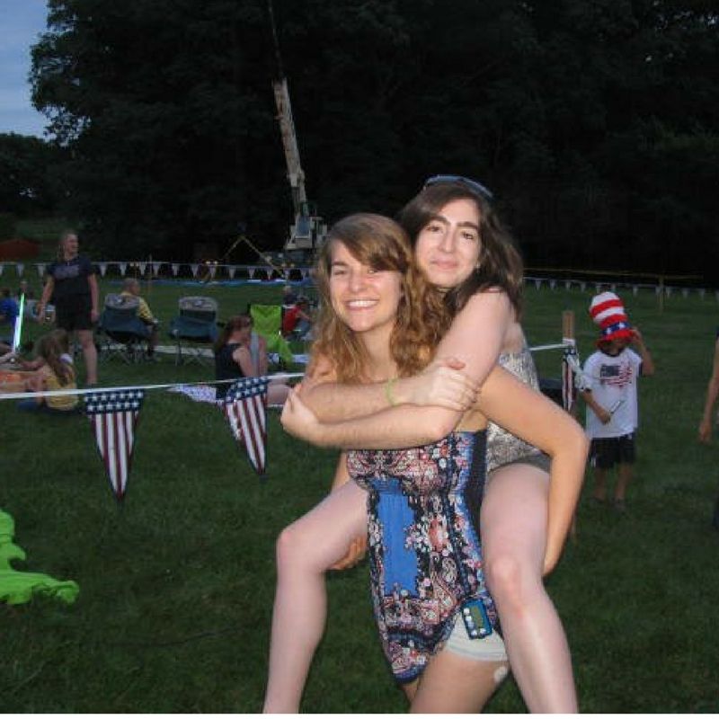 A woman is carrying another woman on her back in a field