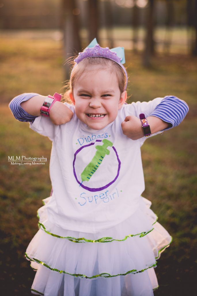 A little girl wearing a purple headband and a white shirt is standing in a field.