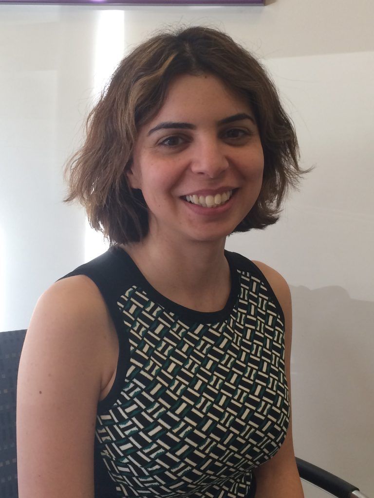 A woman wearing a black and white top smiles for the camera