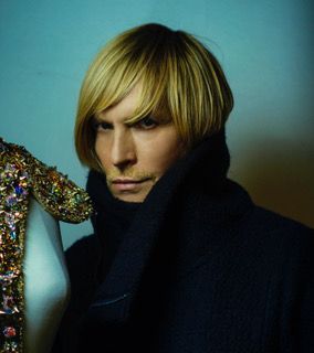 A man with blonde hair is wearing a black scarf around his neck