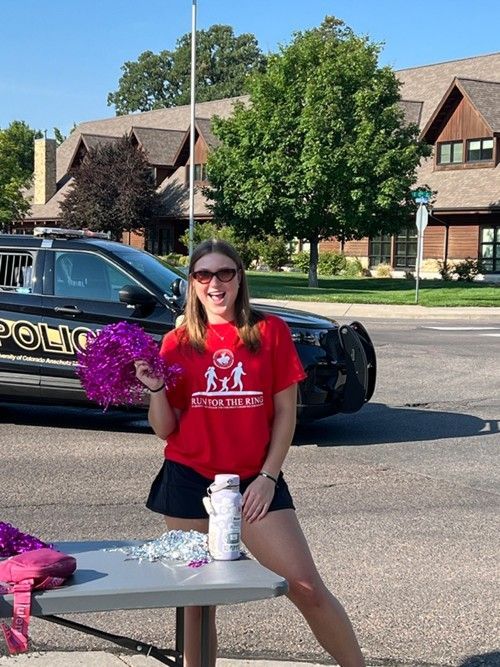 Margot Rea in a red t-shirt volunteering and cheering for runners at CDF's run for the ring 5k