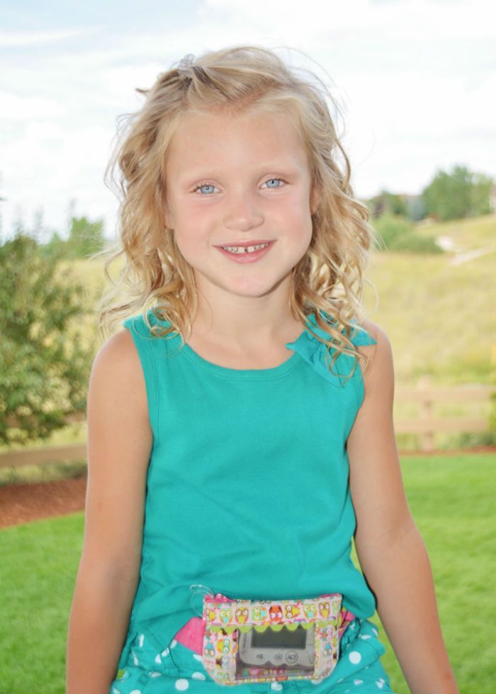 A little girl is wearing a green tank top and polka dot shorts.