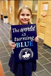 A young girl is holding a sign that says the world is turning blue
