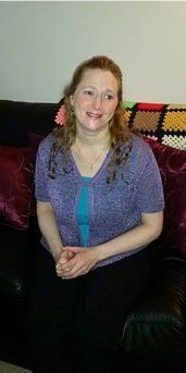 A woman in a purple shirt is sitting on a couch.