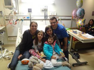 A family is posing for a picture in a hospital room.