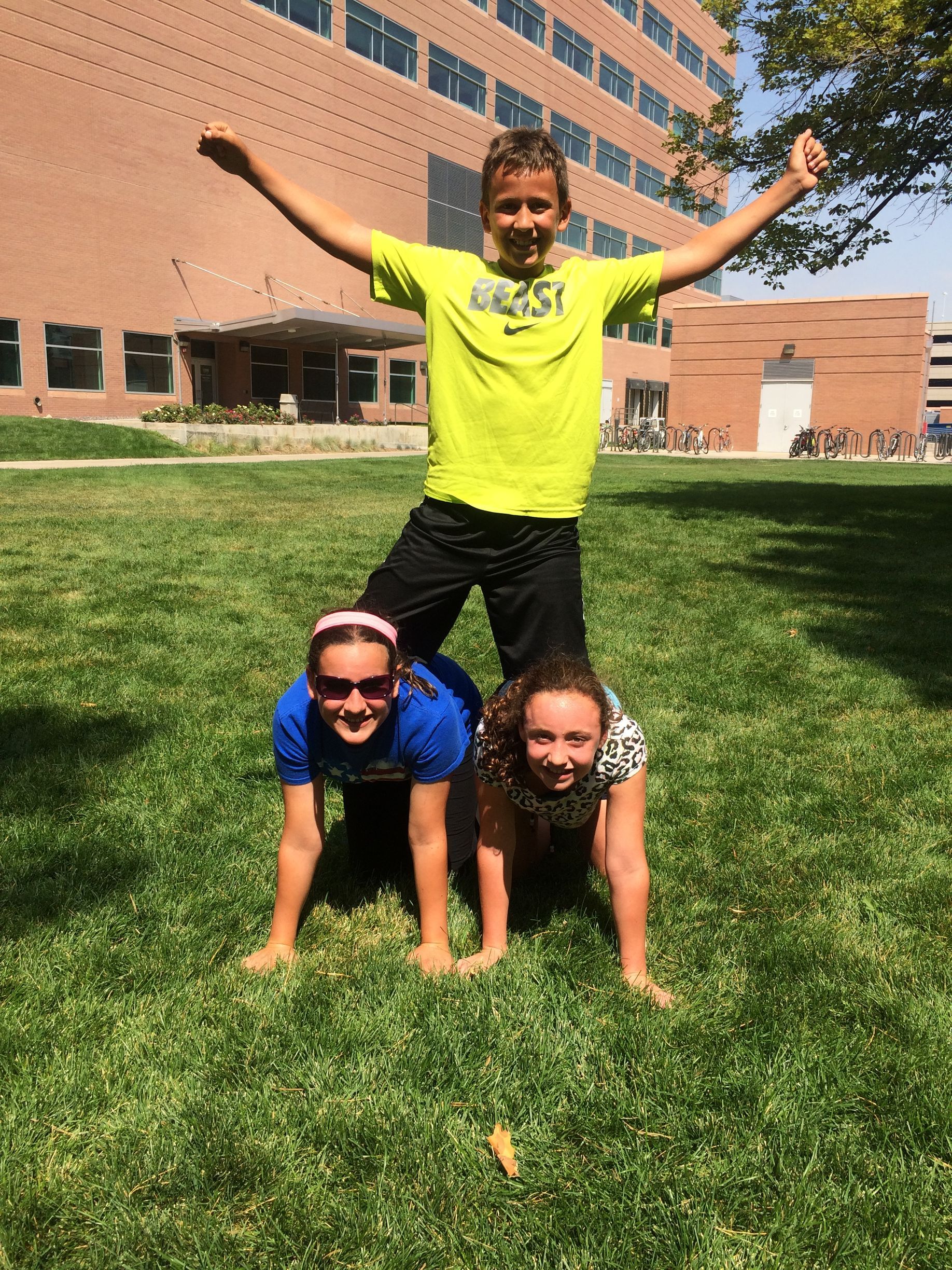 Parker Zarecki and his sisters posing in a pyramid form outside in the grass