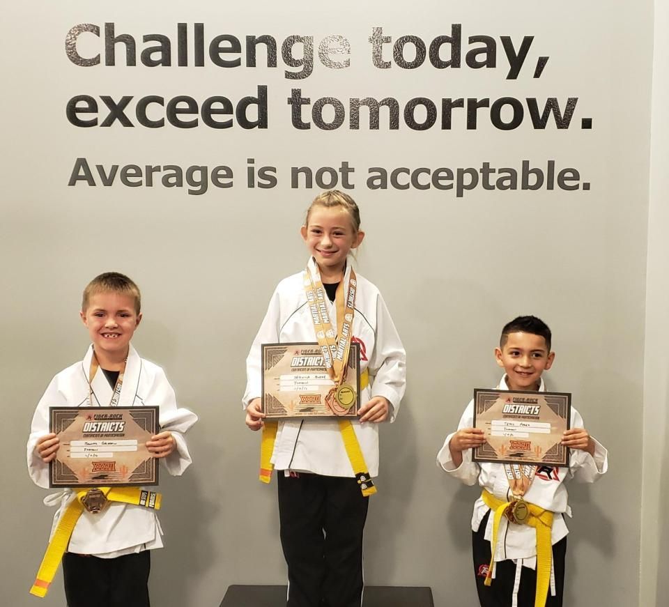 Three children on a podium holding medals for their competition