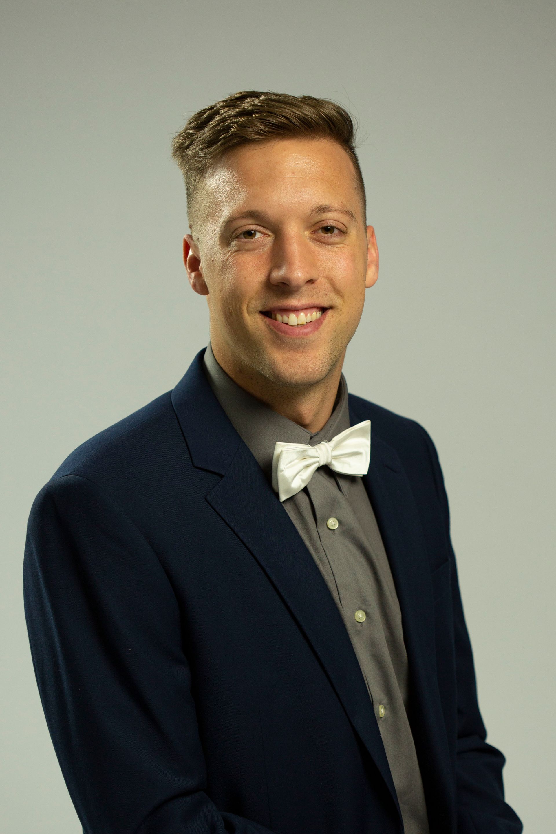 A man in a suit and bow tie is smiling for the camera.