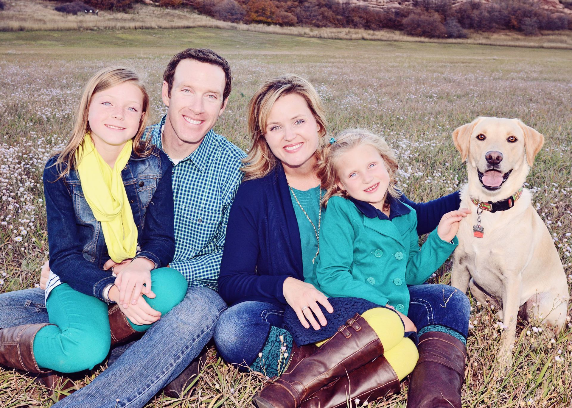 A family posing for a picture with their dog in a field