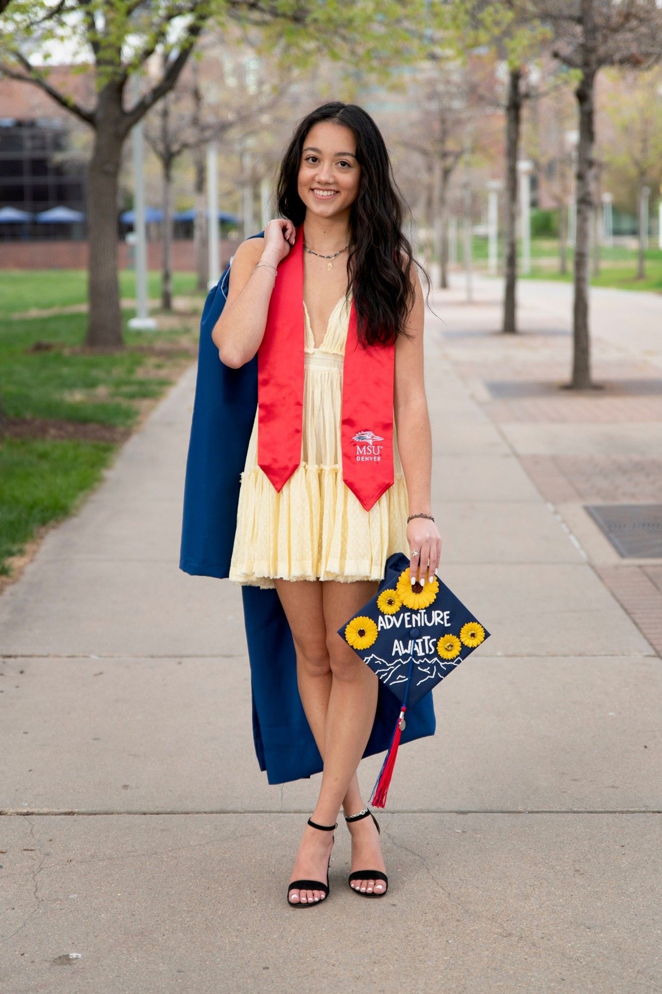 Author Sasha Amiscaray holding her college graduation cap and gown