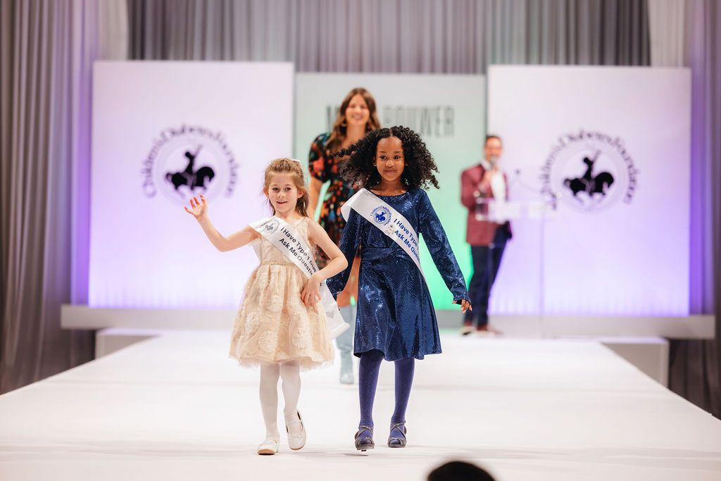 Two little girls walking the runway at the Brass Ring Luncheon & Fashion Show. 