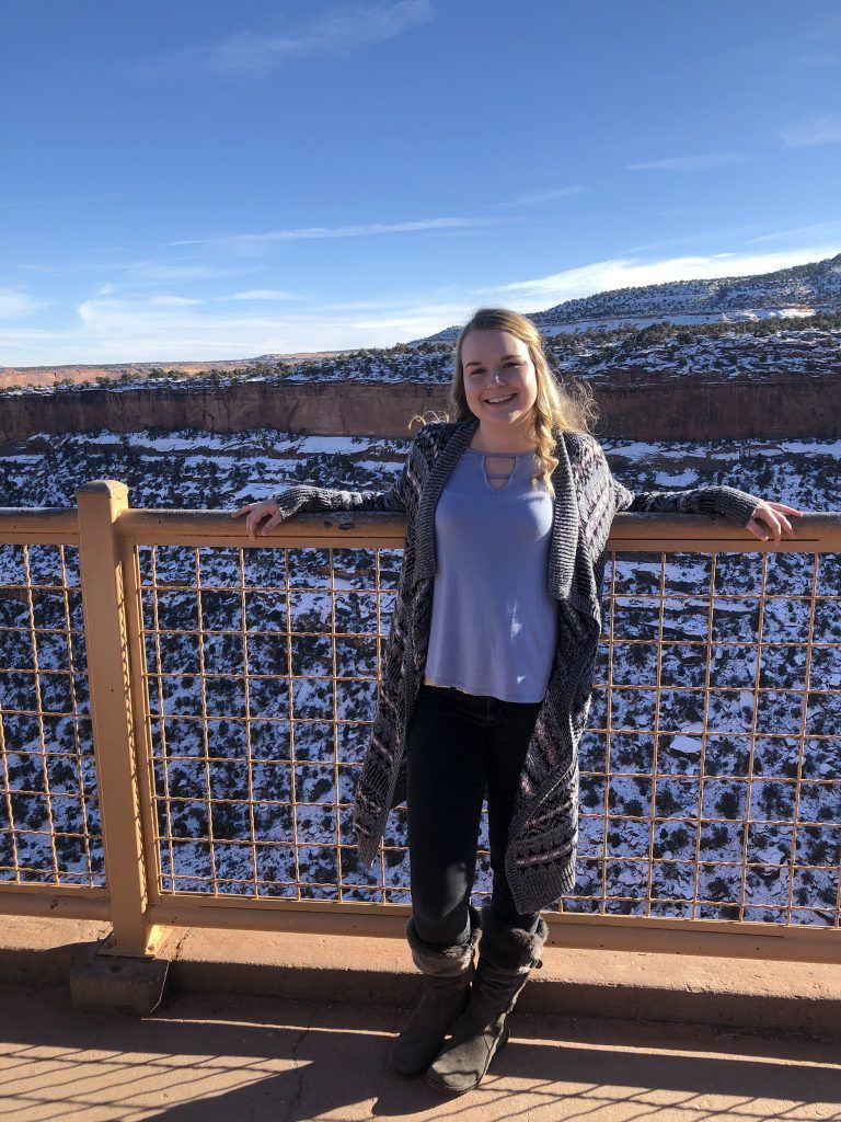 A woman is standing next to a railing overlooking a snowy landscape.