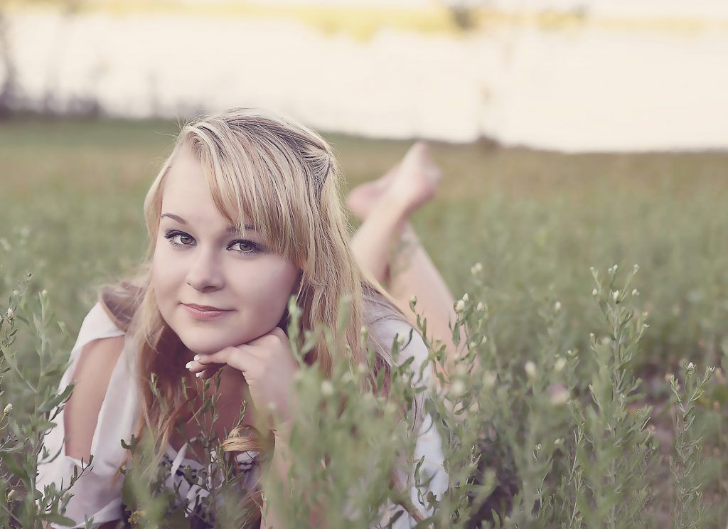 A woman is laying on her stomach in a field of grass.
