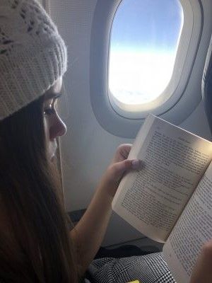 A woman is sitting on an airplane reading a book.