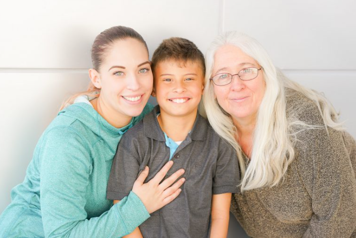 Mother, young son and grandmother posing together and smiling.
