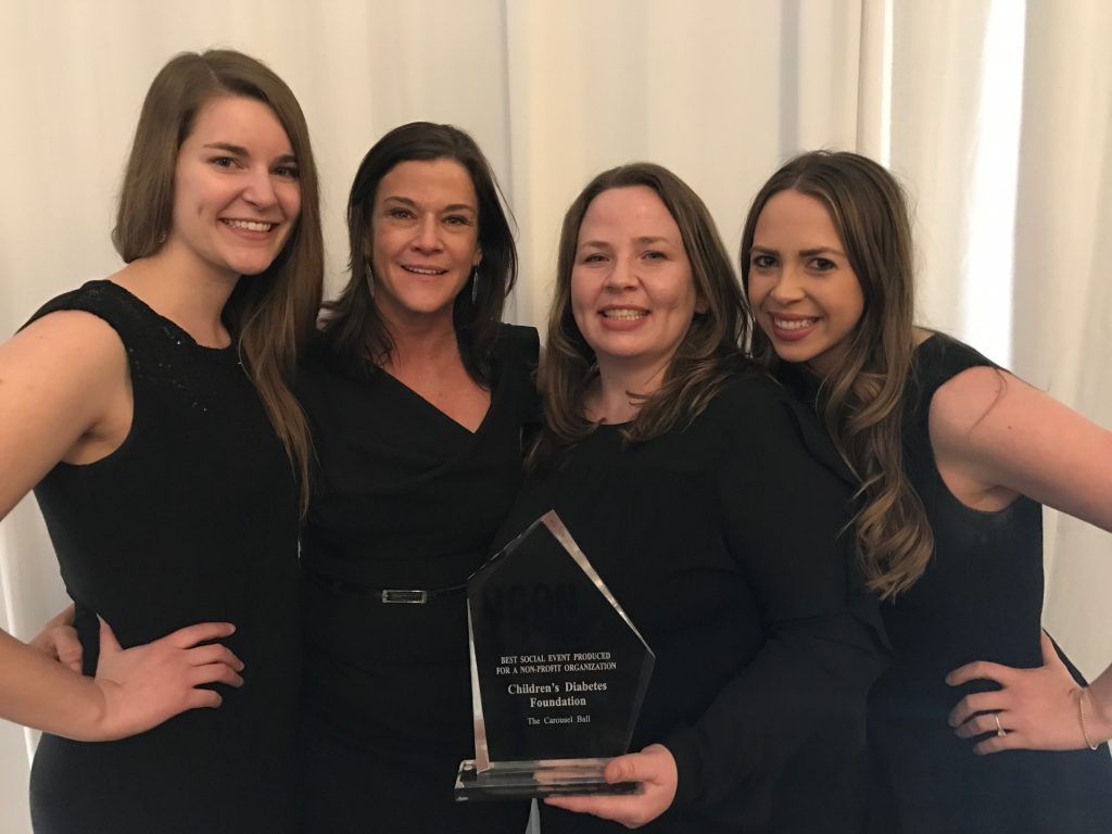 A group of women standing next to each other holding a trophy.