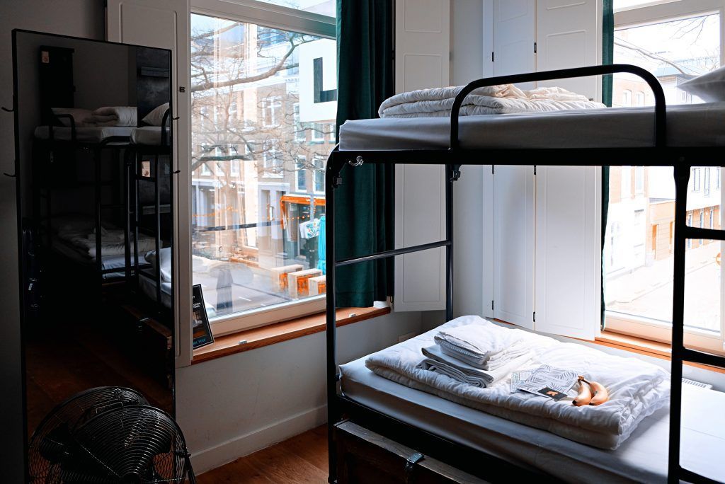 A bunk bed is sitting in a room next to a window.