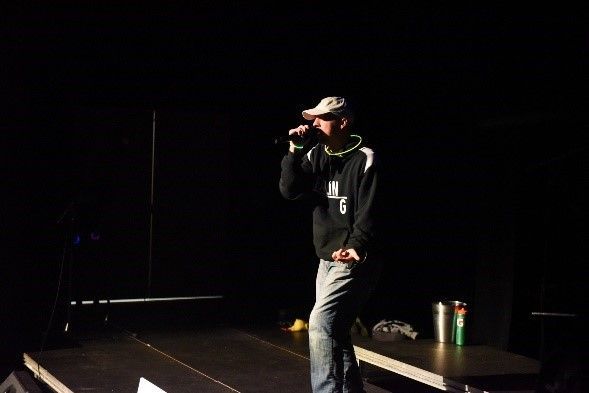 A man is standing on a stage singing into a microphone.