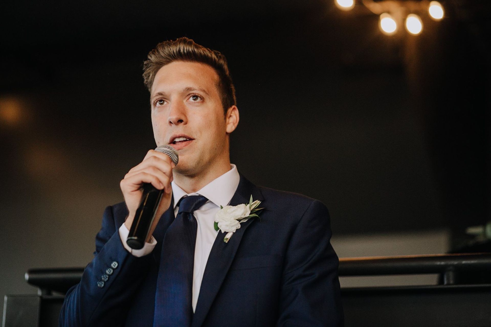 A man in a suit and tie is holding a microphone.