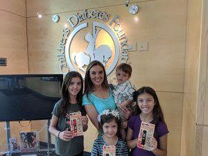 A woman and three children are posing for a picture in front of a children 's foundation logo.