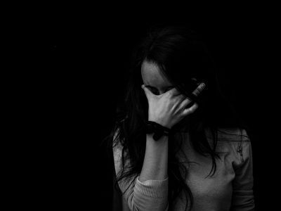 A woman is covering her face with her hand in a black and white photo.