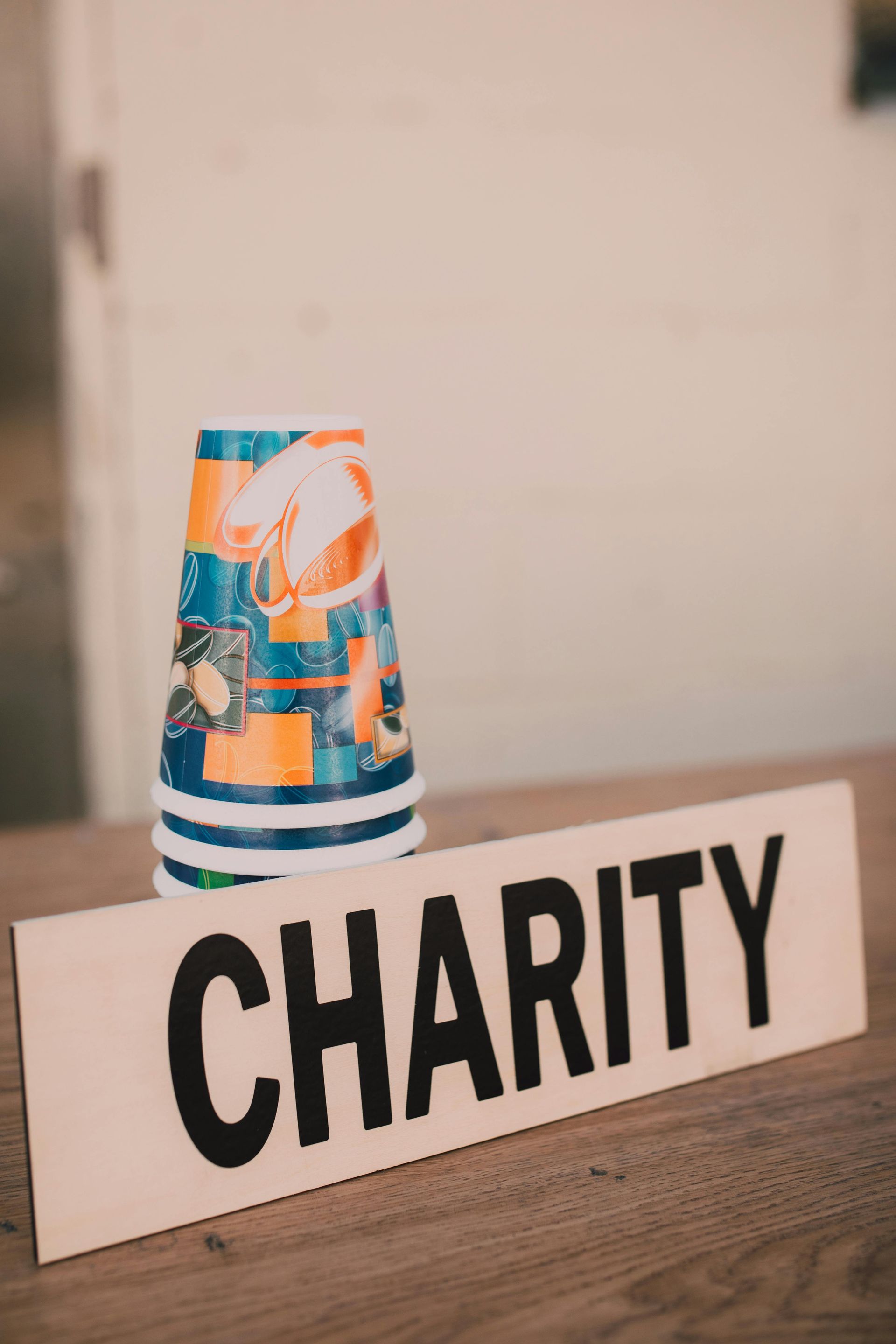 A sign that says charity next to a cup on a table.