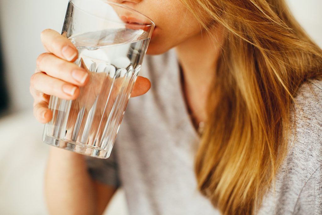 A woman is drinking a glass of water.