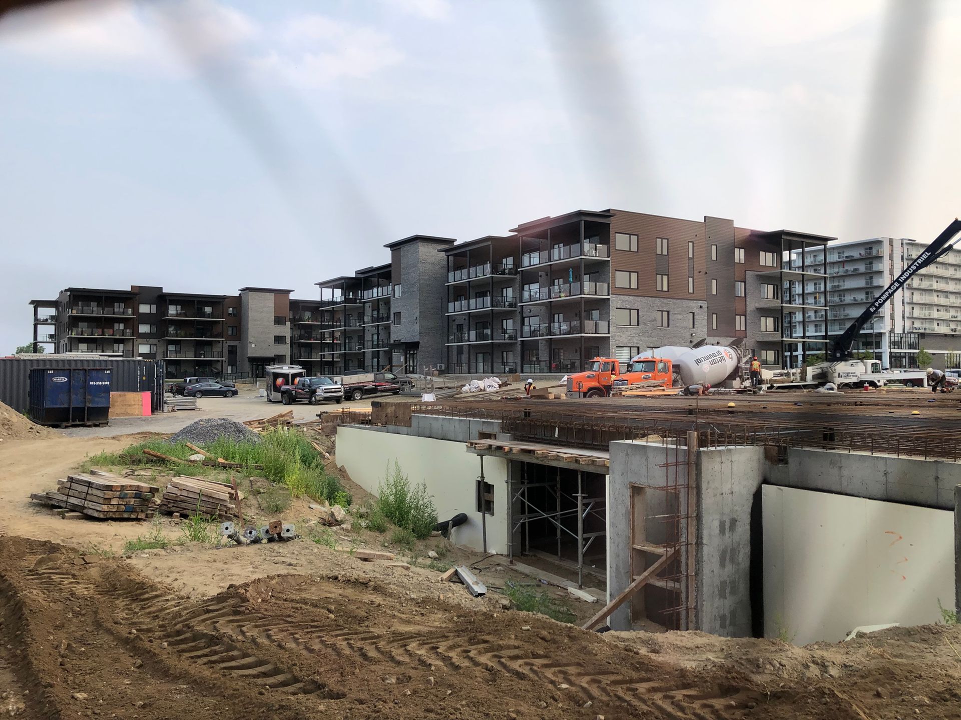 Chantier de construction avec plusieurs immeubles de plusieurs étages à différents stades d'achèvement. Ciel bleu.
