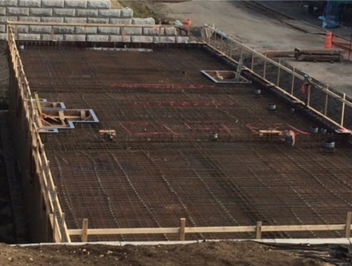 Chantier de construction avec treillis d'armature et coffrage en bois préparé pour le coulage du béton.