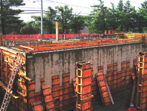 Chantier de construction avec coffrages en bois pour murs en béton.