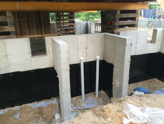 Fondations d'un bâtiment en construction, soutenues par des poutres en bois.