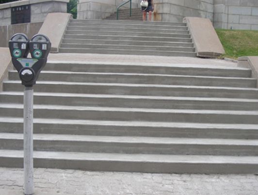 Horodateur devant un long escalier en béton menant à l'étage.