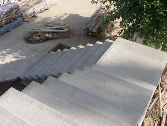 Escalier en béton menant à l'étage, avec des matériaux de construction en arrière-plan.
