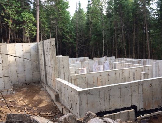 Murs de fondation en béton en construction dans une zone boisée.