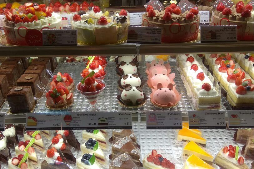 A pastry display case filled with various Japanese-style cakes and desserts, featuring strawberry 