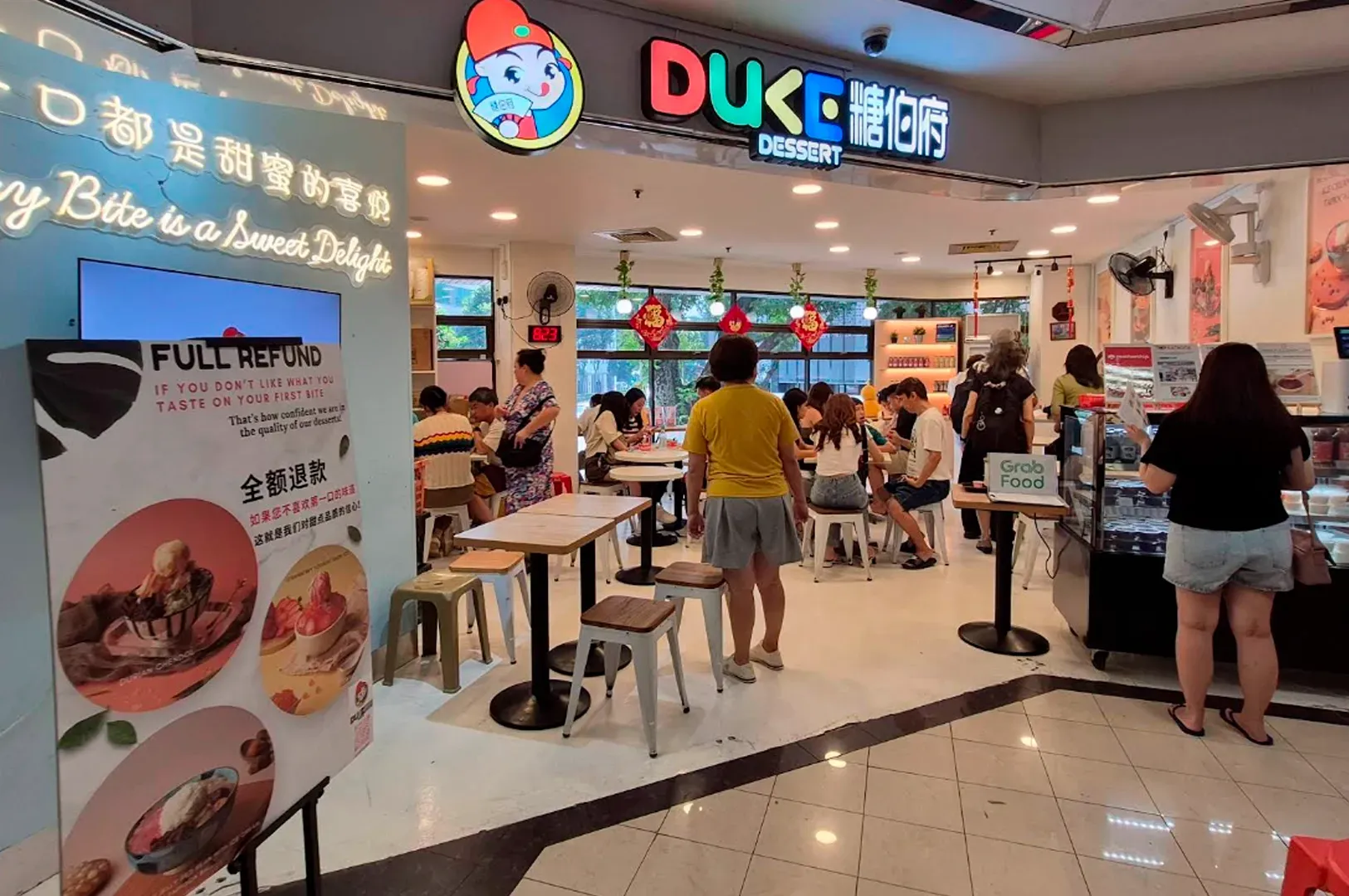 A wide-angle, eye-level photograph shows the brightly lit storefront and interior of Duke Dessert