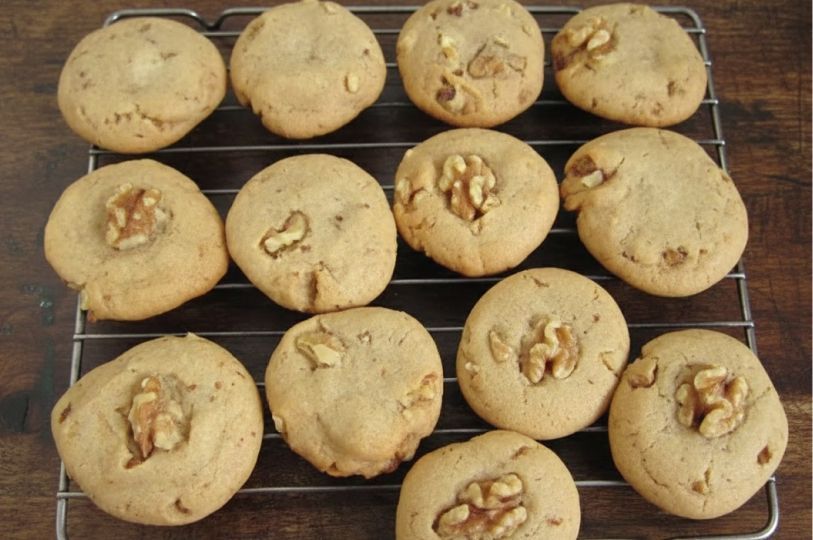 Twelve round, golden-brown honey walnut cookies cooling on a wire rack. 