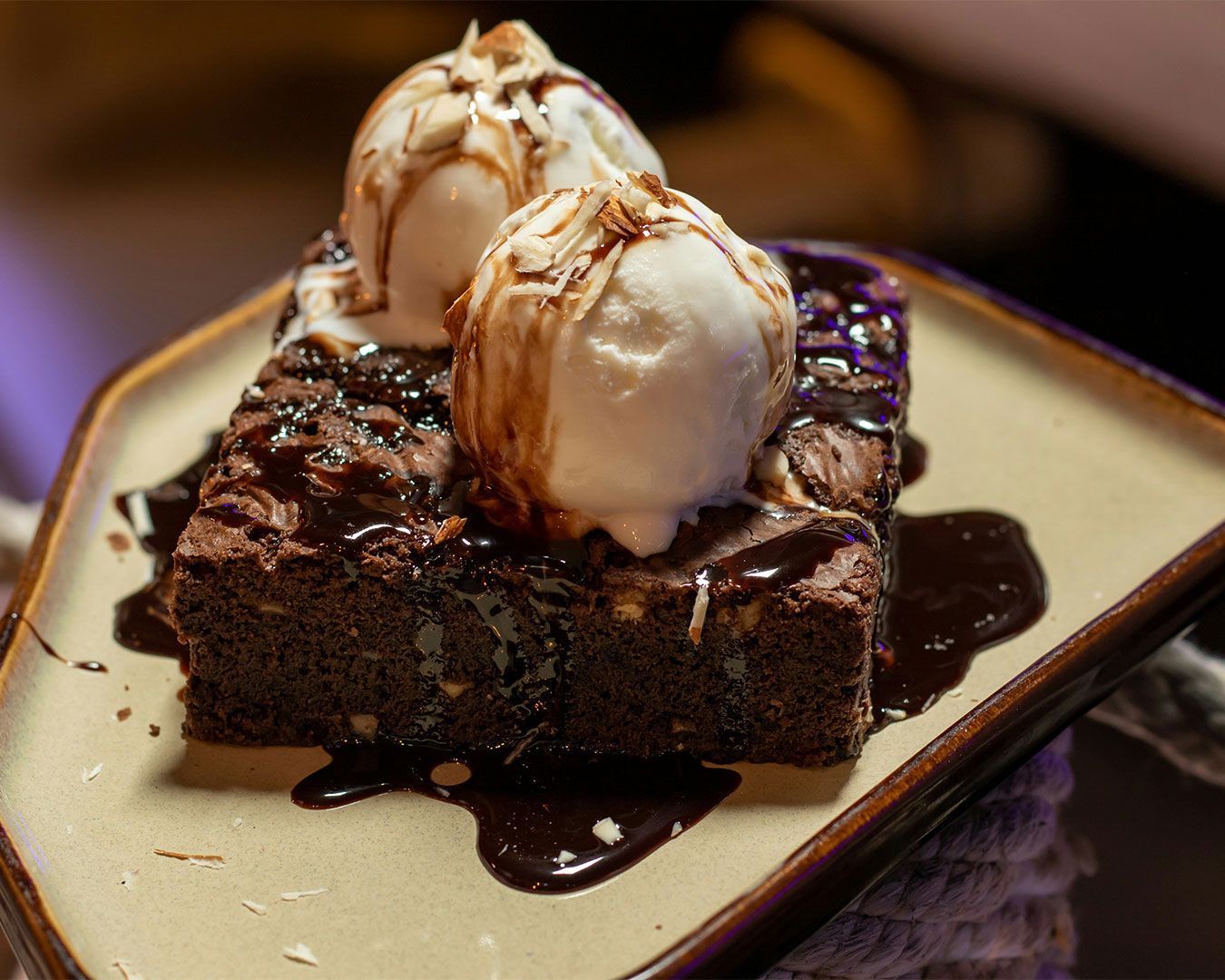 A warm, dense chocolate brownie topped with a melting scoop of vanilla ice cream, creating a rich contrast of hot and cold textures.