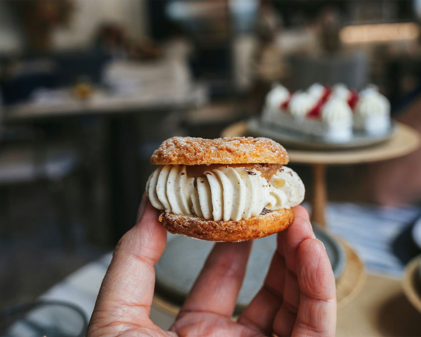 A hand presenting a contemporary Asian-style dessert with refined plating and delicate garnishes.