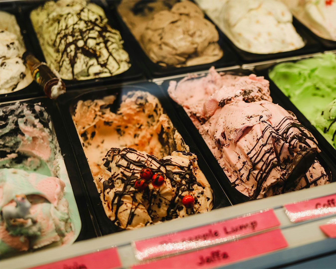 A colourful display of assorted ice cream flavours in a glass freezer, showing multiple textures and vibrant tones ready to be served.