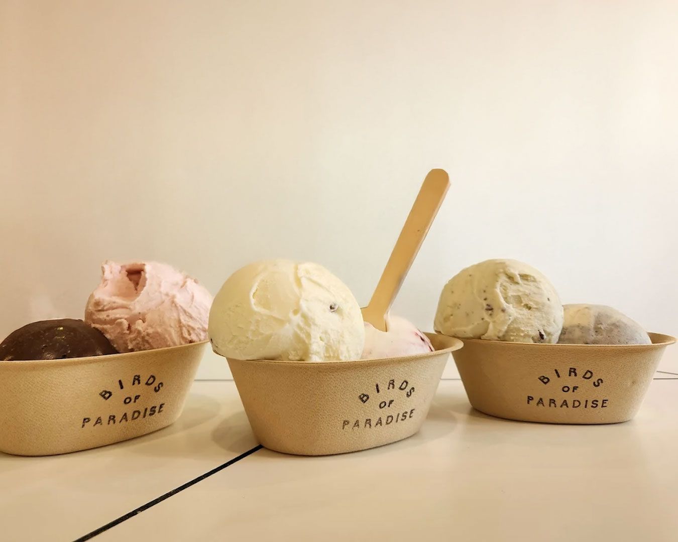 A scoop of botanical-inspired ice cream served in a minimalist cup, highlighting delicate floral and fruit flavours.