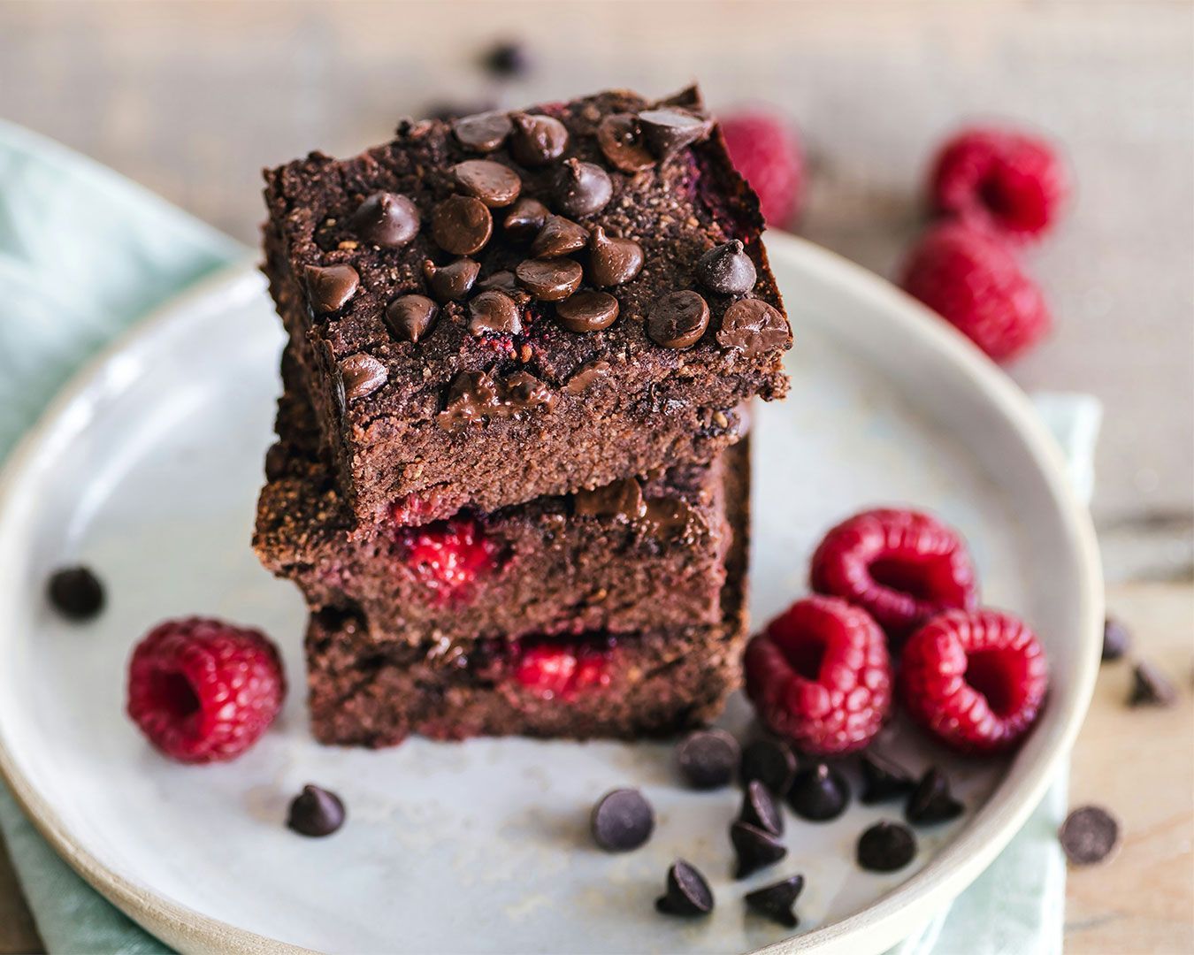 A rich, fudgy chocolate brownie topped with fresh berries and a light dusting of icing sugar, served on a simple dessert plate.