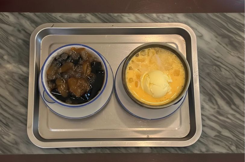 A top-down view of two bowls of traditional Asian desserts served on a silver tray.